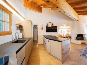 A modern kitchen with wooden beams, a built-in island, and a fireplace in the living area. - Bündastrasse 22 OG Appartement/Fewo, Dusche oder Bad, WC 6 1/2-Zimmerwohnung by Interhome (Davos)