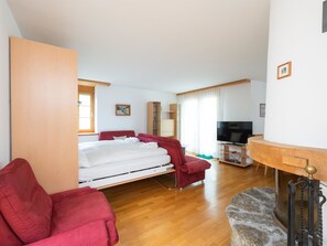 A hotel room with a bed, a TV, a desk, and a red chair. - Skistrasse 8B Appartement/Fewo, Dusche oder Bad, WC 3½-Zimmerwohnung by Interhome (Davos)
