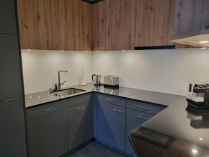 A modern kitchen with a built-in dishwasher, a sink, and a coffee machine. - Skistrasse 8B Appartement/Fewo, Dusche oder Bad, WC 3½-Zimmerwohnung by Interhome (Davos)