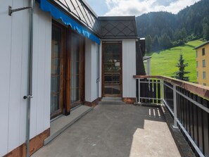 Een gebouw met een balkon, een deur en uitzicht op een groen landschap.