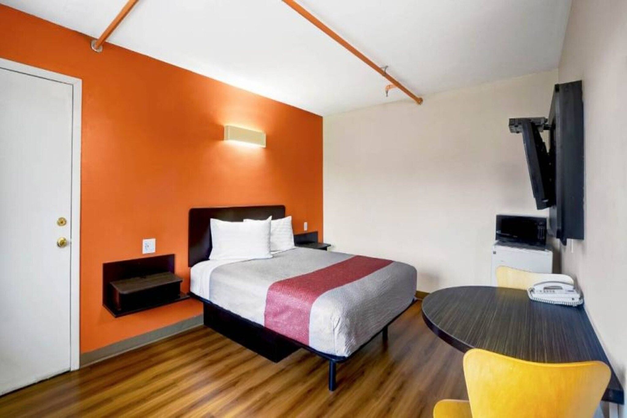 A hotel room with a bed, a desk, a chair, and a television.