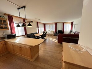 A spacious living area with a wooden dining table, a sofa, and a TV. - Bünda Residenz 101 Appartement/Fewo, Dusche oder Bad, WC 4½-Zimmerwohnung by Interhome (Davos)