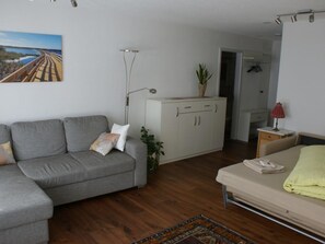 A living room with a grey sofa, a beige sofa, a cabinet, a plant, and a painting of a bridge. - Clematis 1 Appartement/Fewo, Dusche oder Bad, WC 3½-Zimmerwohnung by Interhome (Wiesen)