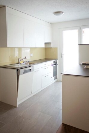 A modern kitchen with white cabinets, a stainless steel countertop, and a built-in oven. - Clematis 1 Appartement/Fewo, Dusche oder Bad, WC 3½-Zimmerwohnung by Interhome (Wiesen)