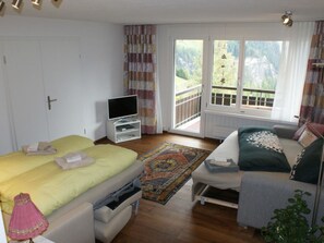 A bedroom with a bed, a TV, a balcony, and a view of the outdoors. - Clematis 1 Appartement/Fewo, Dusche oder Bad, WC 3½-Zimmerwohnung by Interhome (Wiesen)