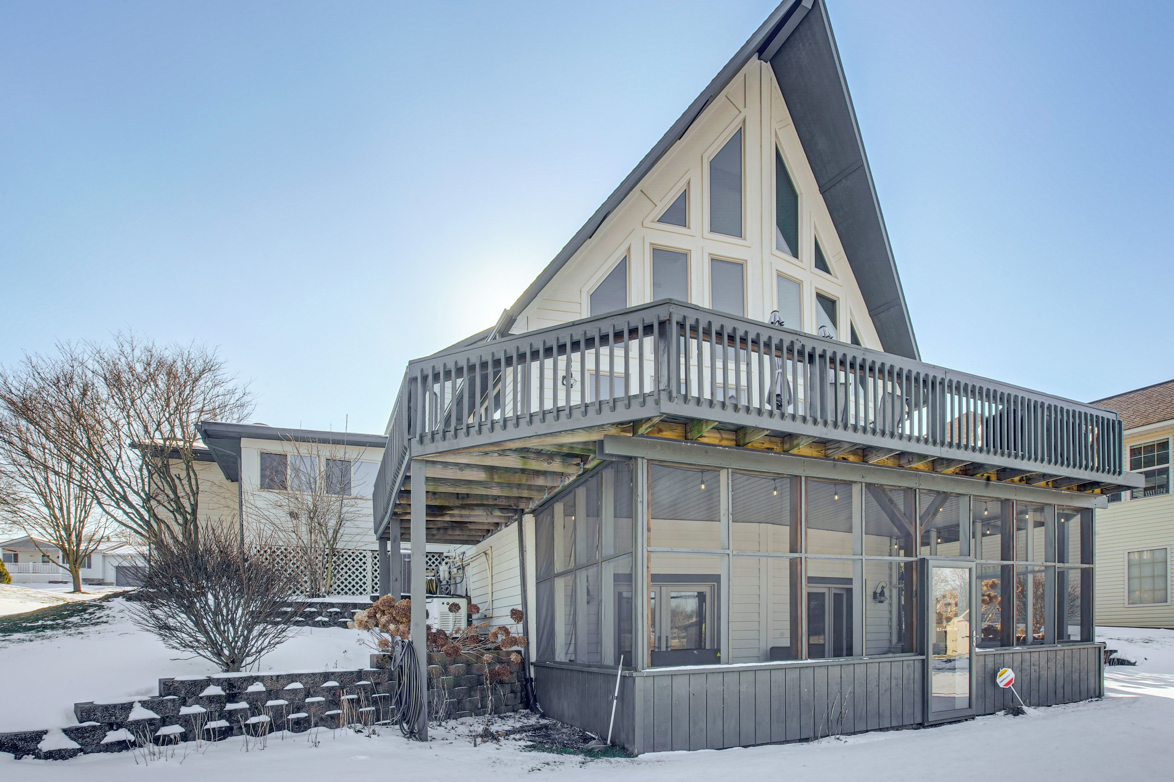 A modern building with a large glass facade, a balcony, and a snow-covered ground.