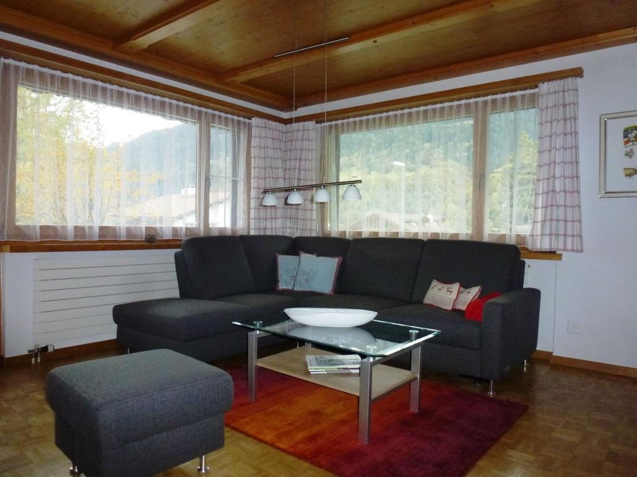 En moderne stue med sofa, skammel og sofabord i glas.