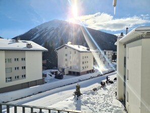 Ein Wohngebiet mit schneebedecktem Boden, Gebäuden mit vielen Fenstern und einem Berg im Hintergrund.
