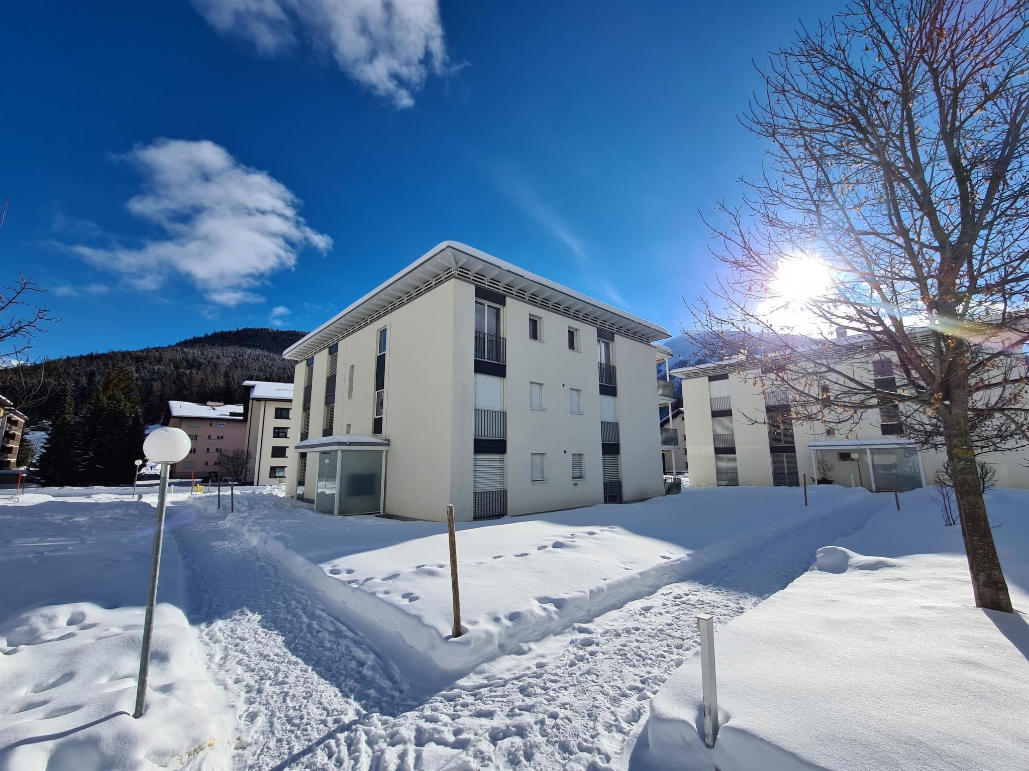 A multi-story building with a flat roof, surrounded by snow-covered ground and a clear sky.