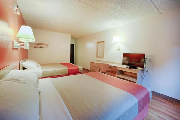 Une chambre d’hôtel avec deux lits, un bureau, une télévision et un miroir.