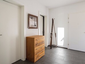 A hallway with a wooden chest of drawers, a framed picture on the wall, and a pair of skis leaning against the wall. - Scarlett Suot 64 Appartement/Fewo, Dusche oder Bad, WC 4-Zimmerwohnung by Interhome (Davos)