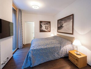 A hotel room with a bed, a TV, a bedside table with a lamp, and two framed pictures on the wall. - Scarlett Suot 64 Appartement/Fewo, Dusche oder Bad, WC 4-Zimmerwohnung by Interhome (Davos)