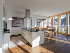 A modern kitchen with a central island, wooden flooring, and a dining area with a view of mountains. - Scarlett Suot 64 Appartement/Fewo, Dusche oder Bad, WC 4-Zimmerwohnung by Interhome (Davos)
