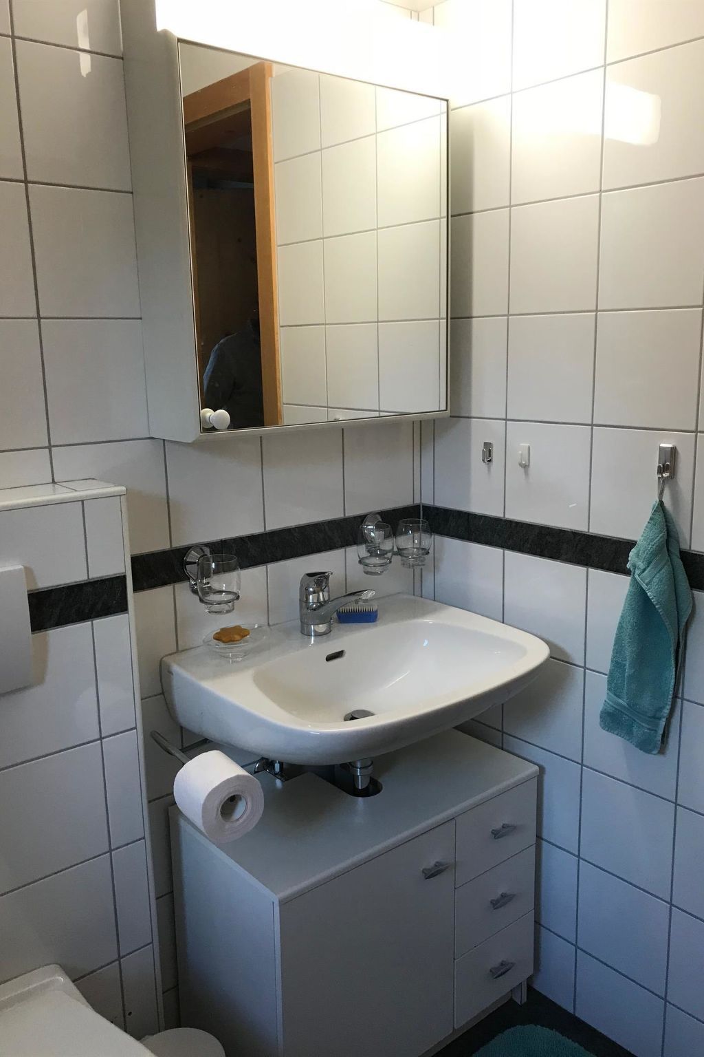 A bathroom with a white sink, mirror, and tiled walls.