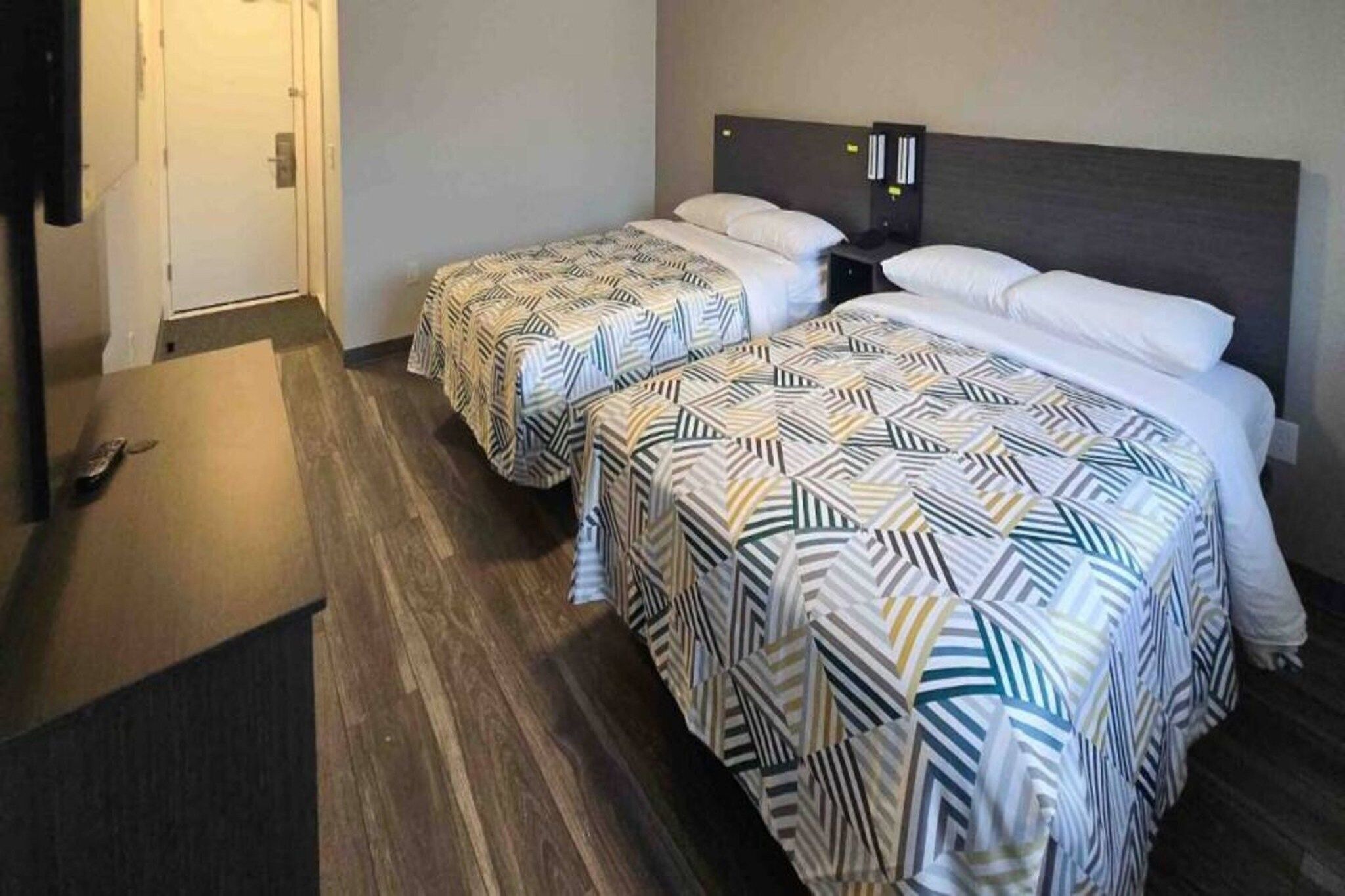 Una habitación de hotel con dos camas, un escritorio y una puerta.