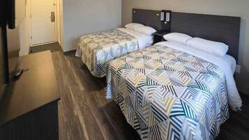 Una habitación de hotel con dos camas, un escritorio y una puerta.