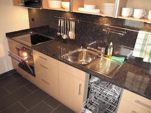 A modern kitchen with stainless steel appliances, a granite countertop, and a dish rack. - Golfresidenz 47 Appartement/Fewo, Dusche oder Bad, WC 4½-Zimmerwohnung by Interhome (Davos)