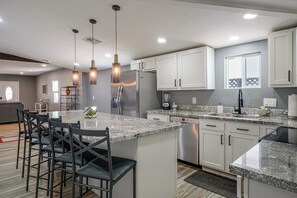 A modern kitchen with a central island, bar stools, stainless steel appliances, and pendant lighting. - 2 Mi to U of A & UMC! Desert Extended Stay (Tucson)