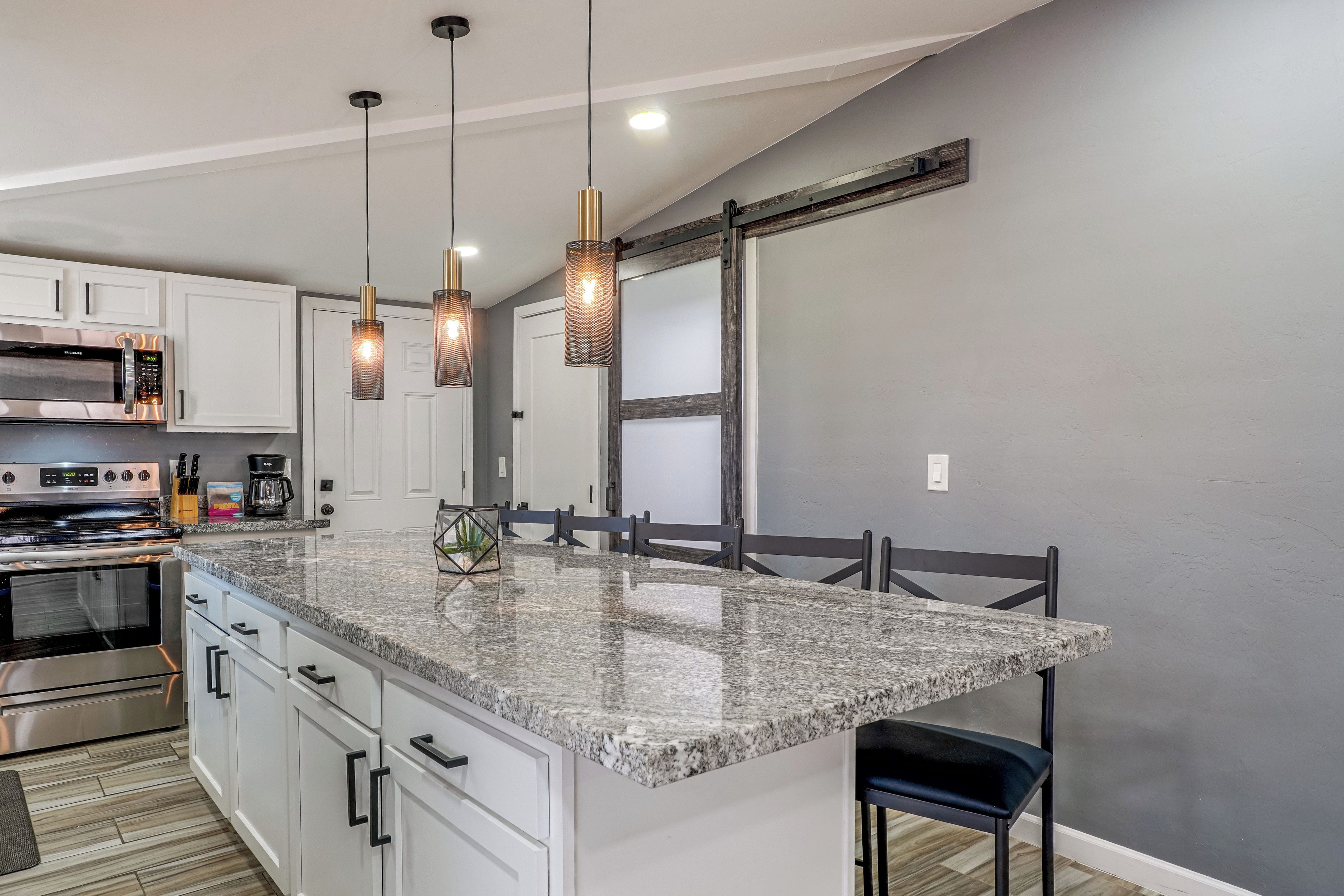 A kitchen with granite countertops, a stainless steel range, and a large island with bar stools.