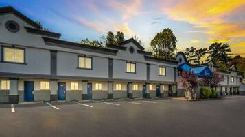 Une rangée de chambres de motel avec un parking devant.