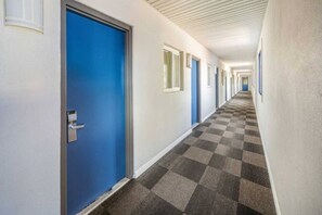 A hotel corridor with blue doors, checkered carpet, and white walls.