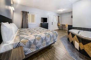 Una habitación de hotel con una cama, un baño con bañera, un escritorio y una silla.