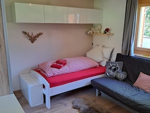 Ein kleines, gemütliches Schlafzimmer mit einem Bett, einer Bank und einem Schlafsofa.