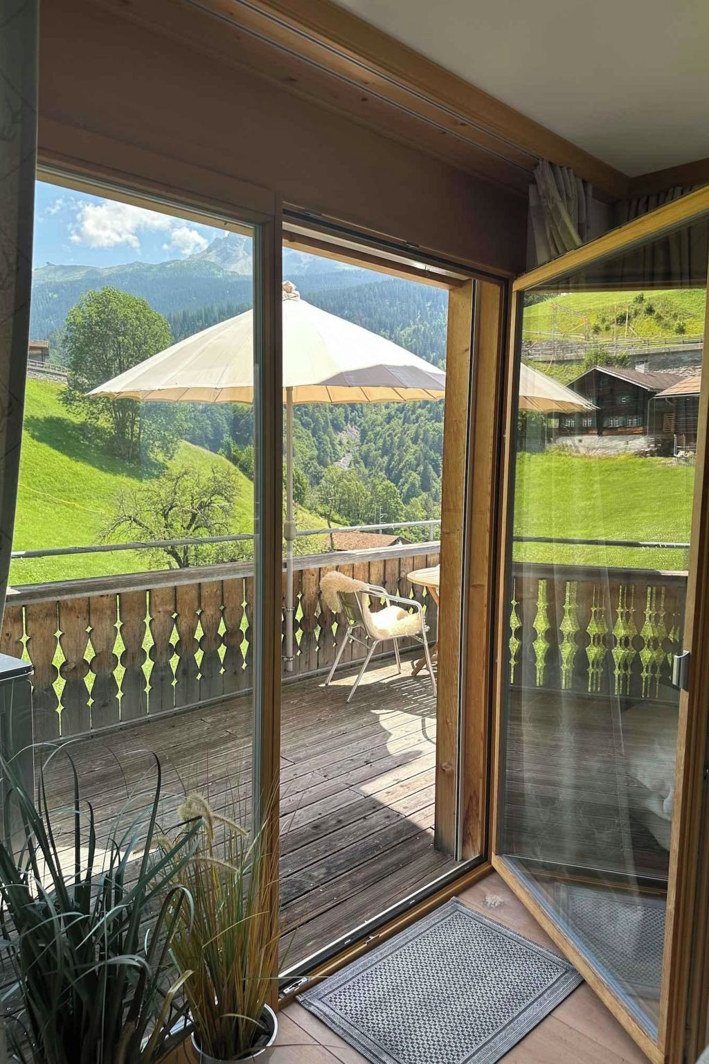 Un balcon offrant une vue sur un paysage montagneux, une terrasse en bois et une chaise.