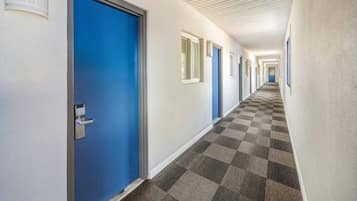 Een hotelgang met blauwe deuren, een geruit tapijt en witte muren.