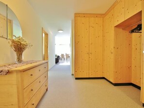 A hallway with wooden cabinets, a dresser, and a vase with dried flowers. - Auf der Matta E01 Appartement/Fewo, Dusche oder Bad, WC 4½-Zimmerwohnung by Interhome (Davos)