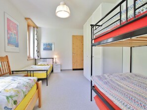 Une chambre de dortoir avec des lits superposés, un bureau, une chaise et un lit avec une literie à motifs floraux.