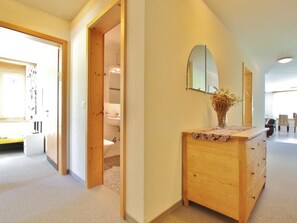 Un couloir avec une commode en bois, un miroir et un vase contenant des fleurs séchées.