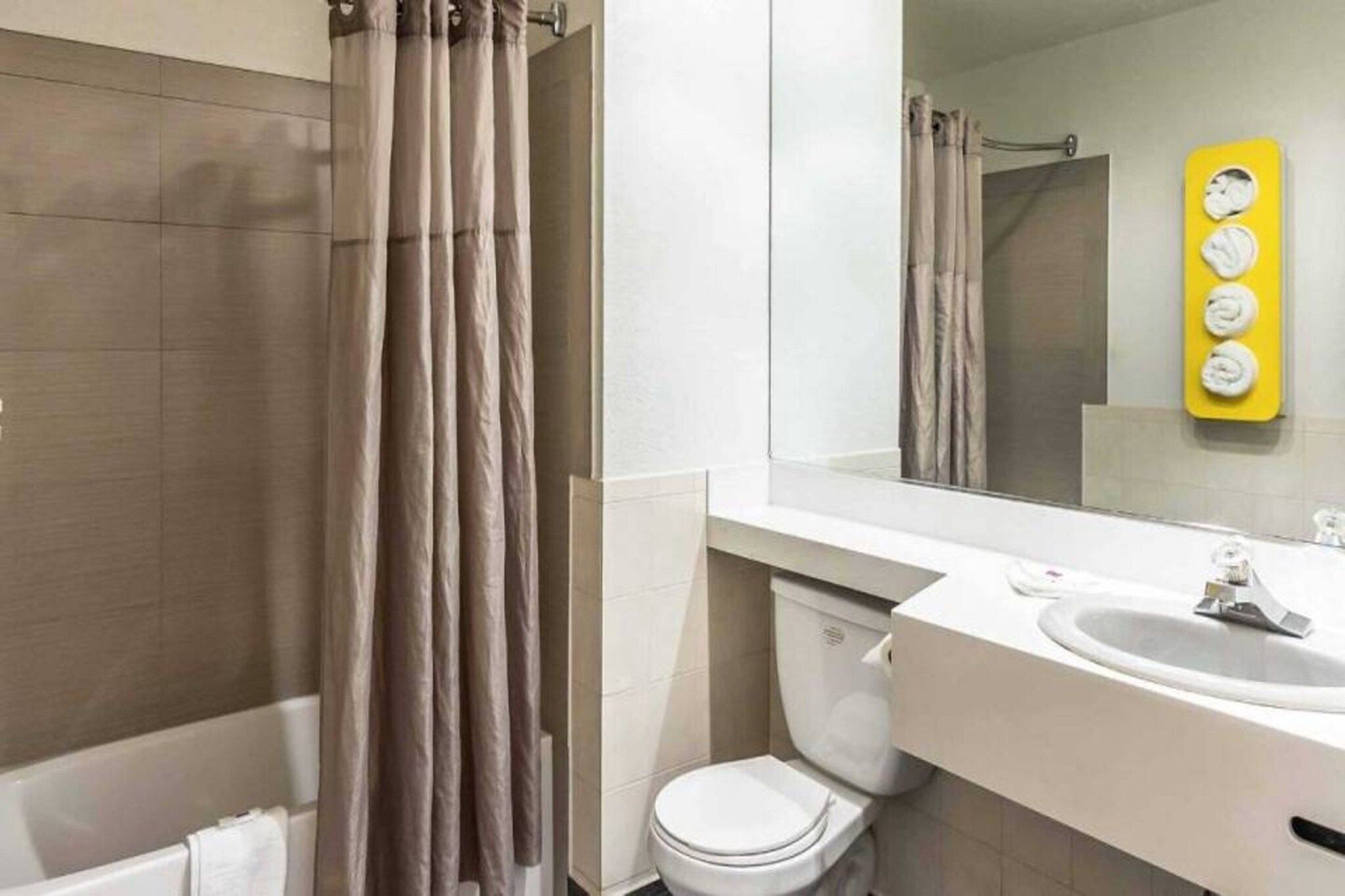 A bathroom with a shower curtain, a toilet, a sink, and a mirror.