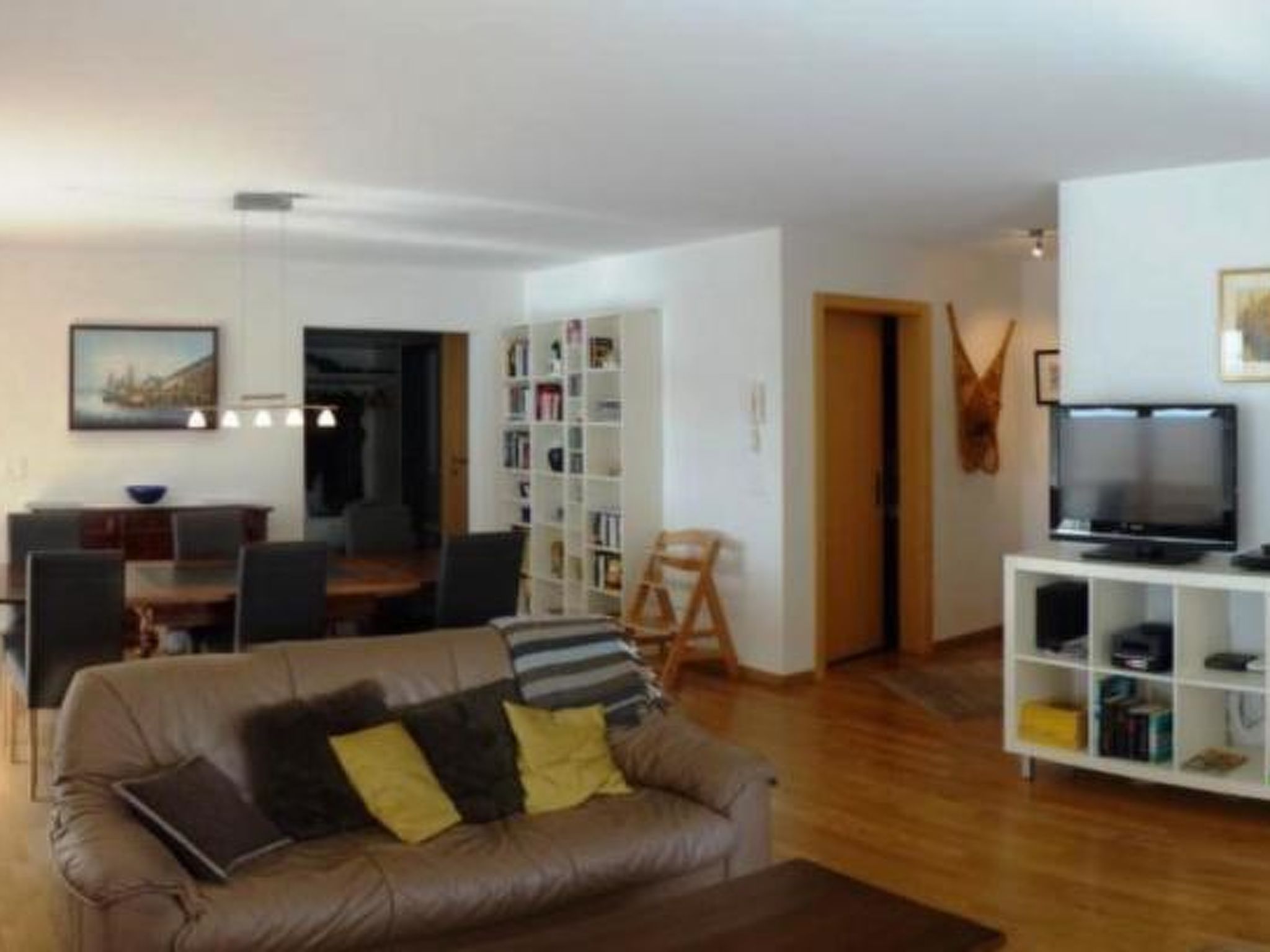 Ein Wohnzimmer mit einer Couch, einem Couchtisch, einem Bücherregal und einem Fernseher.