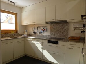 A kitchen with white cabinets, a granite countertop, and a window with a view of a house. - Chesa Silvrettina D4 Appartement/Fewo, Dusche oder Bad, WC 4½-Zimmerwohnung by Interhome (Klosters)