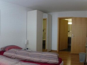 A bedroom with a bed, a bedside lamp, a wardrobe, and an open door leading to a bathroom. - Chesa Silvrettina D4 Appartement/Fewo, Dusche oder Bad, WC 4½-Zimmerwohnung by Interhome (Klosters)