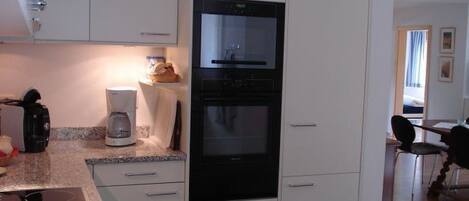 A kitchen with white cabinets, a built-in oven, and a coffee maker.