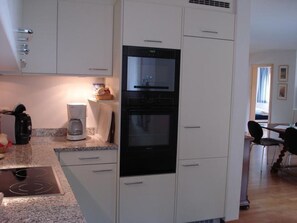 Cuina amb armaris blancs, forn integrat i cafetera.