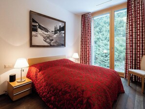 Une chambre d’hôtel avec un grand lit, deux lampes de chevet, un tableau encadré au mur et une fenêtre avec des rideaux.