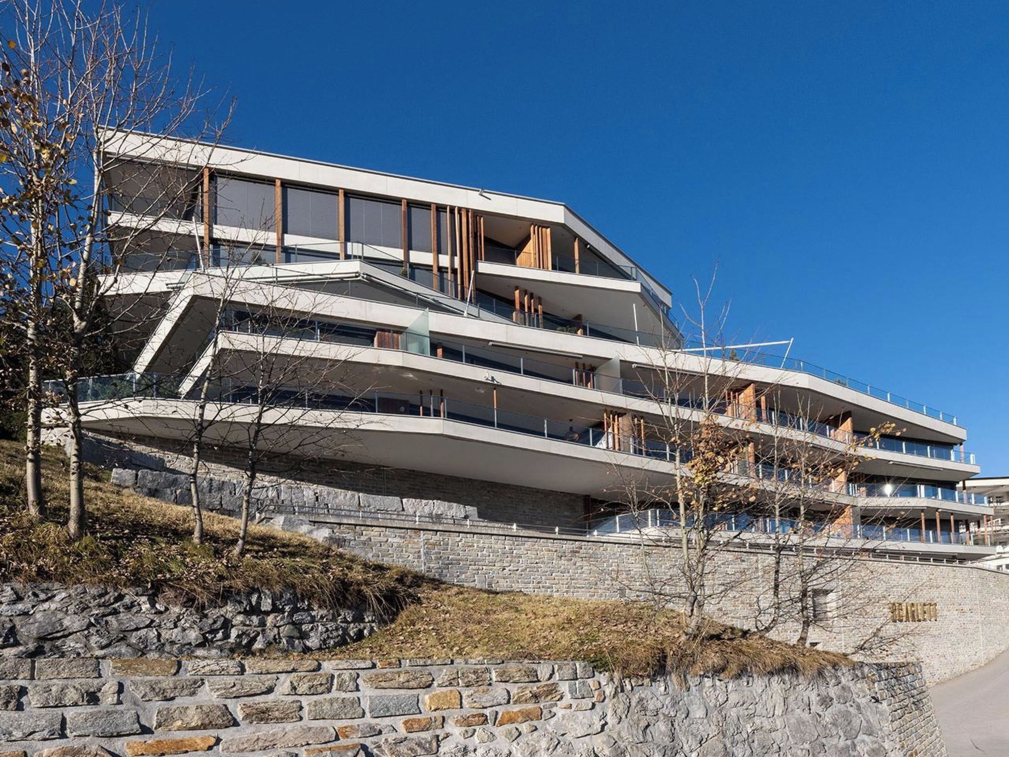 Ein mehrstöckiges Gebäude mit zeitgenössischer Architektur, das Balkone und große Fenster aufweist.