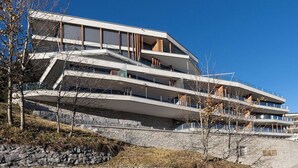 Ein mehrstöckiges Gebäude mit modernem architektonischen Design, mit Balkonen und großen Fenstern.