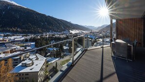 Ein Balkon mit Blick auf eine verschneite Landschaft, eine Brücke und eine Stadt darunter.