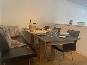 A dining area with a wooden table set for two, a black leather sofa, and a white wall. - Rex 33 Appartement/Fewo, Dusche oder Bad, WC 2½-Zimmerwohnung by Interhome (Davos)