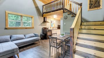 A cozy interior with a loft bedroom, a dining area, and a kitchen.