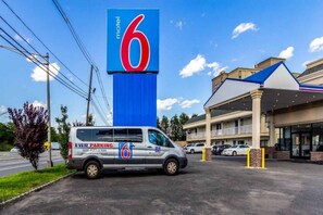 A motel with a prominent blue and red sign, a parking van, and a building with a covered entrance.