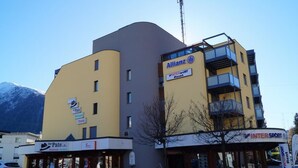 En byggnad med flera våningar, med en skylt som visar texten ”Allianz InterSport Rent” och en mindre skylt med texten ”Der Pate”.