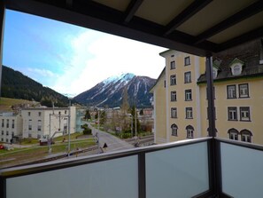 A balcony with a view of a mountain, buildings, and a railway track.