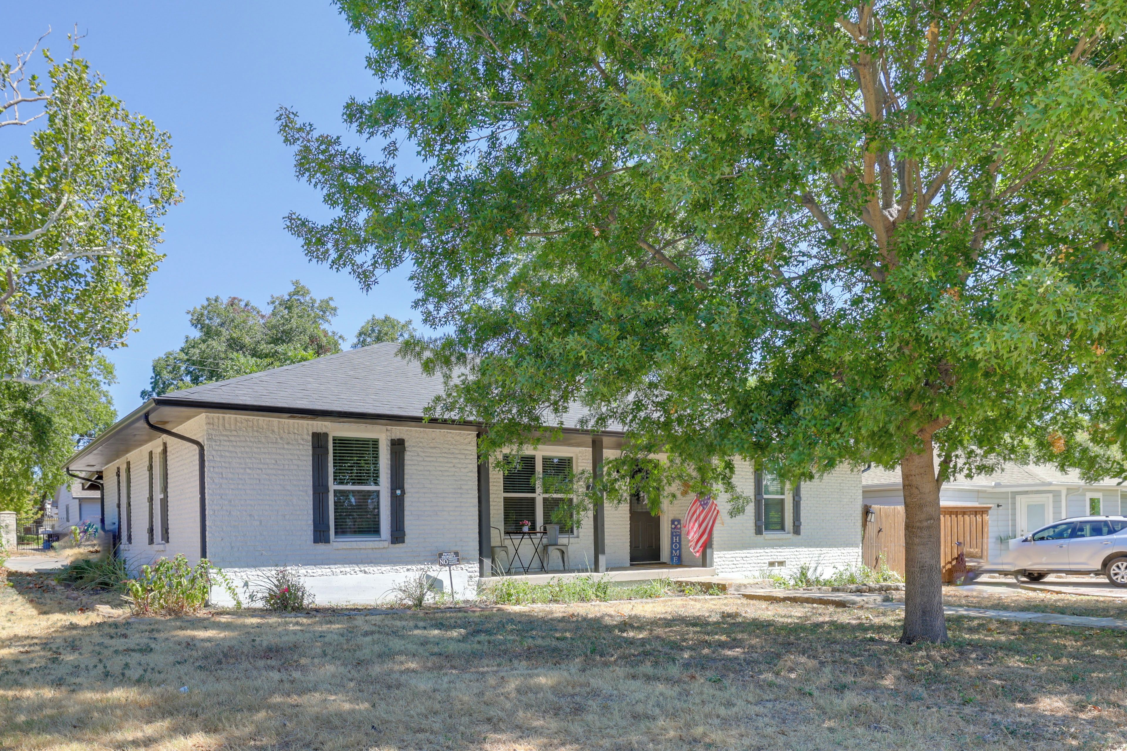 A single-story house with a brick exterior, a front porch, and a flag.