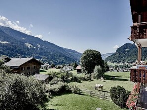 Ländliche Landschaft mit einem großen Baum, einem Holzzaun und einem Gebäude mit schrägem Dach.