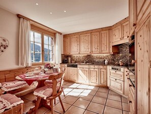 A kitchen with wooden cabinets, a dining table with chairs, and a window with curtains. - Cresta 5 Appartement/Fewo, Dusche oder Bad, WC 4 1/2-Zimmerwohnung by Interhome (Klosters)